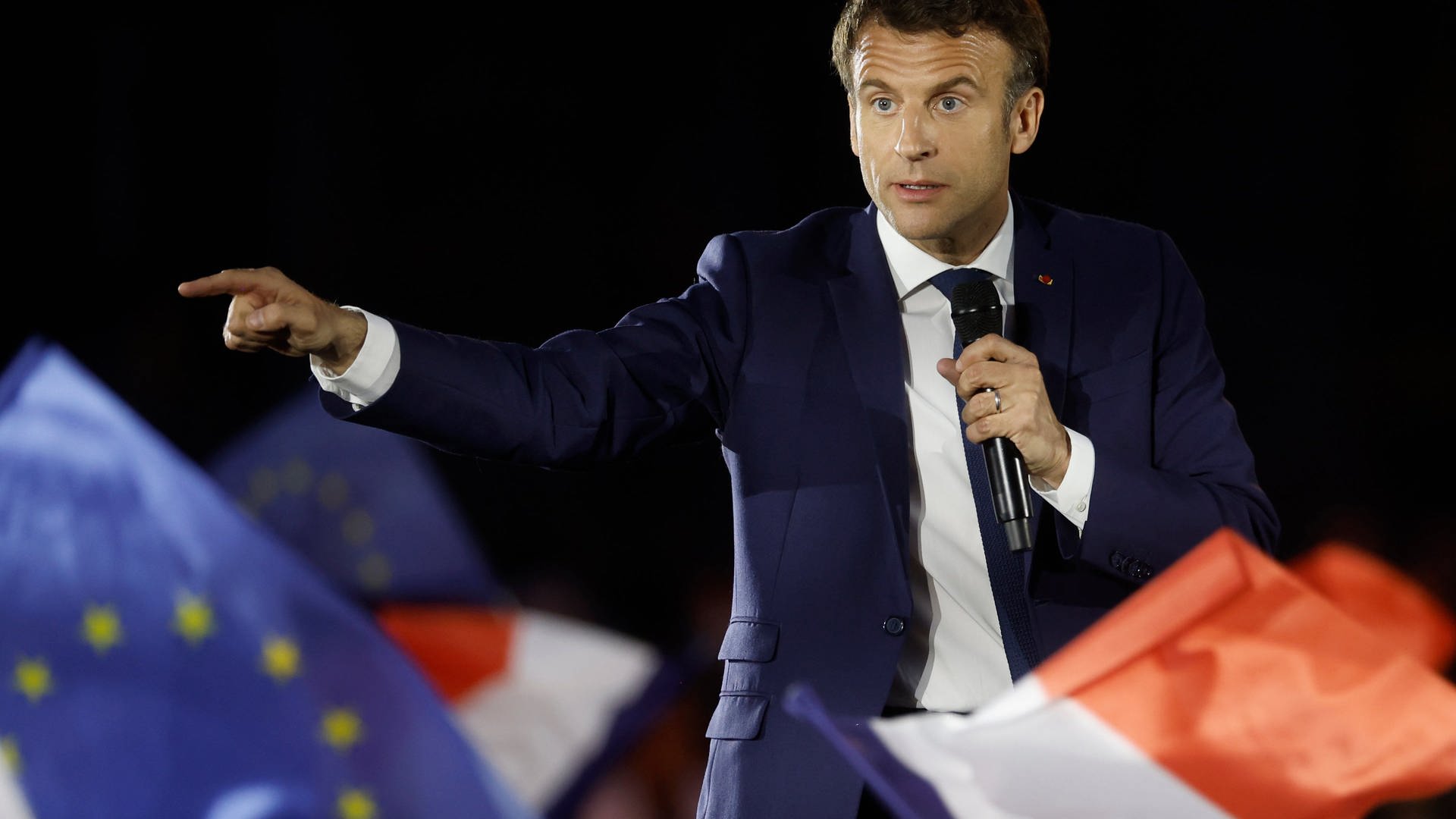 Macron auf einer Bühne. Er spricht eindrücklich zu den Zuschauern. Im Vordergrund: Eine französische und eine europische Flagge. (Foto: picture-alliance / Reportdienste, Picture Alliance)