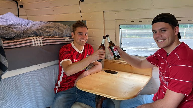 zwei junge Männer in einem Van stoßen mit Bierflasche an (Foto: SWR, Anita Westrup)