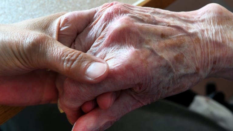 Hand von jüngerer Person hält Hand von älterer Person (Foto: dpa Bildfunk, Holger Hollemann)