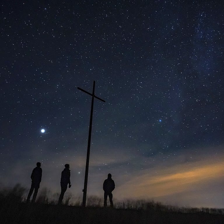 Drei Menschen blicken von einer Bergkuppe in einen Nachthimmel voller Sterne (Foto: SWR)