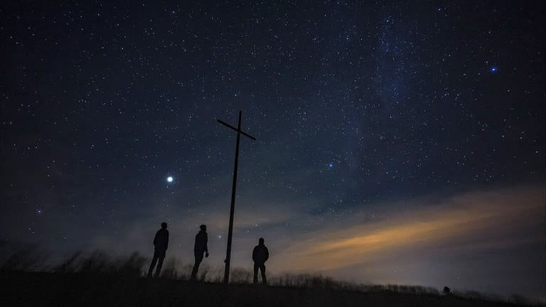 Drei Menschen blicken von einer Bergkuppe in einen Nachthimmel voller Sterne (Foto: SWR)