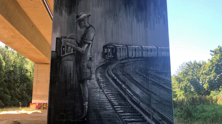 Graffiti in schwarz weiß mit Figur vor abfahrenden Bahn   (Foto: SWR, Laura Könsler)