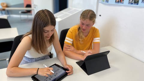 Die Schülerinnen Tabea und Friederike sitzen an einem Schreibtisch in einem Klassenzimmer. (Foto: SWR, Wera Engelhardt)