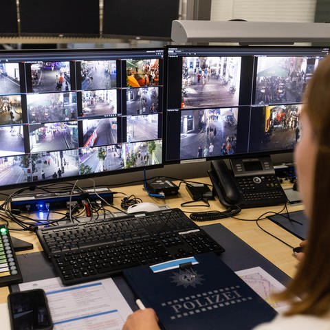 Eine Polizeibeamtin sitzt vor zwei Bildschirmen und sichtet die Bilder, die von den Kameras übertragen werden. (Foto: picture-alliance / Reportdienste, Philipp von Ditfurth)