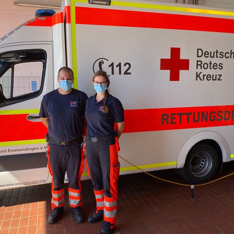 Zwei Menschen in Sanitäteruniform stehen vor einem Rettungswagen.  (Foto: SWR, Sebastian Bargon )