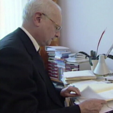 Ex-Erzbischof Robert Zollitsch sitzt an einem Schreibtisch in einem Büro. (Foto: SWR)
