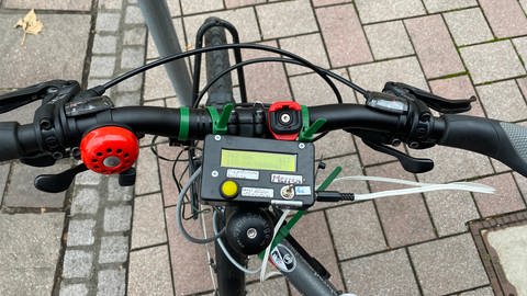 An einem Fahrradlenker ist ein rechteckiges Messgerät angebracht. Es soll den Abstand von Autos messen, die das Fahrrad überholen. (Foto: SWR, Katharina Seeburger)
