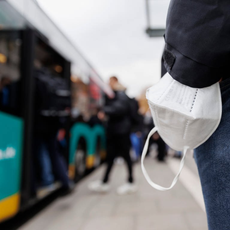 Ein Mann wartet mit einer Maske am Handgelenk auf einen Bus am Stuttgarter Hauptbahnhof. Die digitale Gesundheitsministerkonferenz der Länder berät über die Zukunft der Maskenpflicht. (Foto: dpa Bildfunk, Picture Alliance)