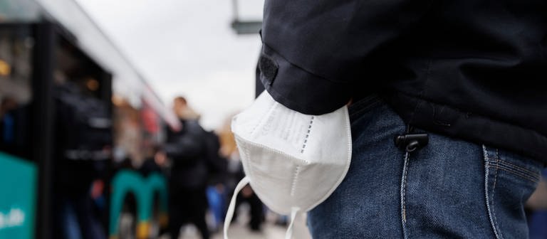 Ein Mann wartet mit einer Maske am Handgelenk auf einen Bus am Stuttgarter Hauptbahnhof. Die digitale Gesundheitsministerkonferenz der Länder berät über die Zukunft der Maskenpflicht. (Foto: dpa Bildfunk, Picture Alliance)