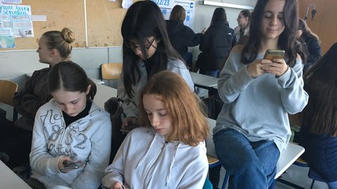 Schülerinnen sitzen in einem Klassenraum und schauen auf ihre Handys. (Foto: SWR, Gabi Krings)