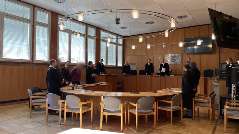 Prozessbeteiligte stehen zur Urteilsverkündung im Gerichtssaal. (Foto: SWR, Paulina Flad)