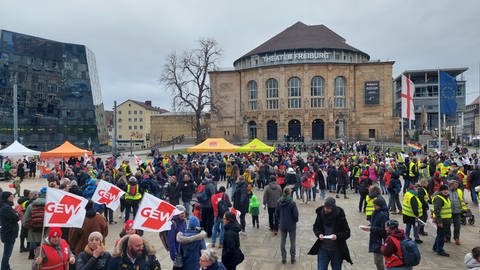 Zahlreiche Menschen mit Fahnen und Warnwesten stehen auf dem Platz der Alten Synagoge in Freiburg. (Foto: SWR)