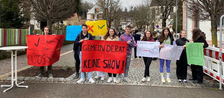 Acht Schülerinnen und Schüler stehen am Anfang der Schönauer die Talstraße. Sie halten Plakate in den Händen und demonstrieren gegen den Bauzaun. Auf den Plakaten steht zum Beispiel "Gemeinderat keine Show". (Foto: SWR, Katharina Seeburger)