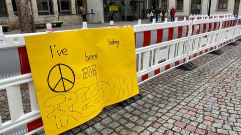 Auf einem gelben Plakat steht in Schwarz: I've been looking for a freedom. Das Plakat hängt an dem rot-weißen Bauzaun, der den Schönauer Schulhof verkleinert. (Foto: SWR, Katharina Seeburger)