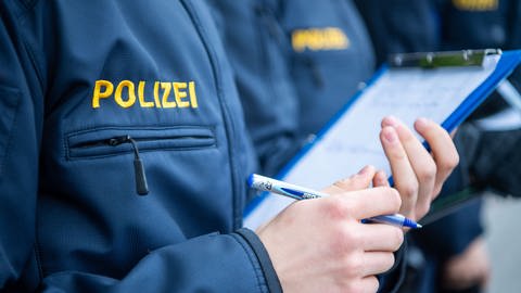 Polizei-Aufschrift auf Jacke eines Polizeischülers oder Polizeischülerin mit Klemmbrett  (Foto: dpa Bildfunk, Lino Mirgeler)
