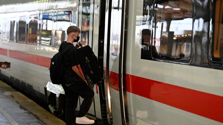 Ein ICE der in einem Bahnhof steht. Ein Mann steigt mit seinem Koffer ein.  (Foto: picture-alliance / Reportdienste, Roberto Pfeil)