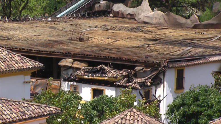 Zu sehen ist der Schaden nach dem Brand im Europapark. Das Bild ist von oben aufgenommen. Auf einem Hausdach ist verkohltes Holz zu sehen. Am Horizont sieht man die Achterbahn Euro Mir (Foto: SWR)