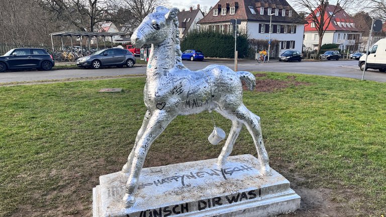 "Happy New Year" und "Wünsch dir was" mit dem Freiburger Holbeinpferd. Das Kult-Pony erstrahlt im Silberglanz. Auch unsere SWR-Reporterin Paula Zeiler hat sich verewigt. Ihr Wunsch für 2024: Frieden. (Foto: SWR, Paula Zeiler)