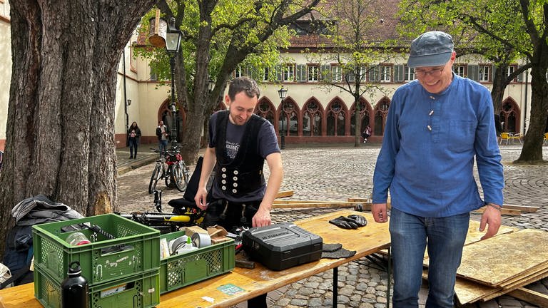 Vor dem Freiburger Rathaus liegen bereits Holzlatten auf dem Platz. Aus einem Kleinlaster laden Menschen weiteres Material. (Foto: SWR, Paula Zeiler)