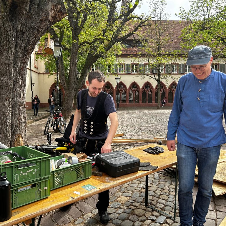 Vor dem Freiburger Rathaus liegen bereits Holzlatten auf dem Platz. Aus einem Kleinlaster laden Menschen weiteres Material.