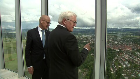 Bundespräsident Steinmeier steht neben Rottweils Oberbürgermeister Ralf Broß. Sie blicken vom Elevator Testturm hinunter auf Rottweil. Der Himmel ist wolkenverhangen, es regnet. Von oben sind die roten Dächer von Rottweil zu sehen, außen rum grüne Felder und Bäume (Foto: SWR)
