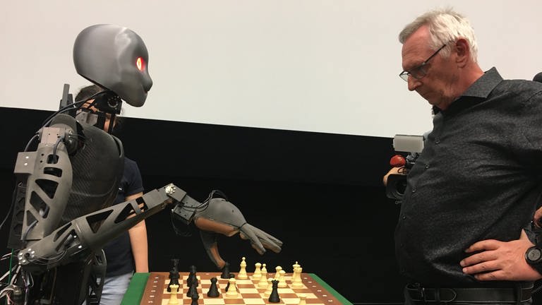 Roboter Sweaty und sein Gegner Michael Maly stehen am Schachbrett