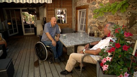 Zwei Männer, einer im Rollstuhl, sitzen am Tisch (Foto: SWR, Moritz Sucker)