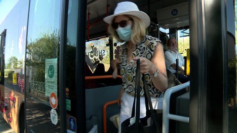 Eine Frau steigt mit Maske aus einem Bus (Foto: SWR)