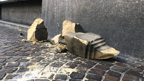 Mehrere Trümmerteile aus beigem Sandstein liegen auf dem Bürgersteig. (Foto: SWR, Dinah Steinbrink)