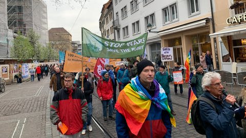 Menschen mit Fahnen und Bannern laufen durch die Freiburger Innenstadt (Foto: SWR)