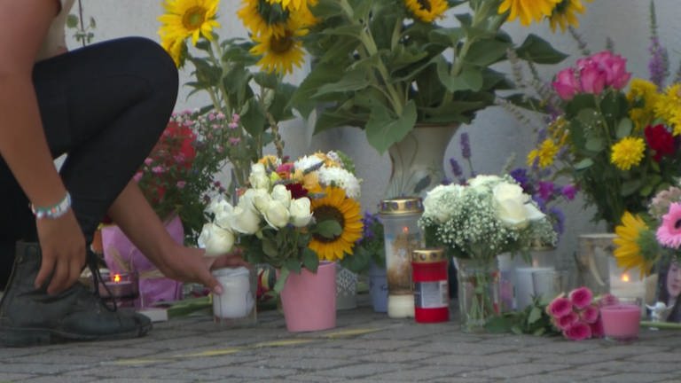 Kerzen und Blumen stehen auf dem Boden. Auf einer Tafel steht "Fly". (Foto: SWR)