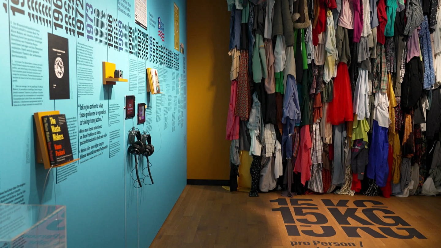 Kleider hängen an einer Wand darunter Kiloangaben (Foto: srf)
