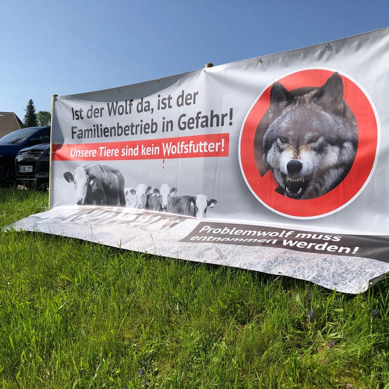 Ein Plakat an einem Zaun mit der Aufschrift: "Ist der Wolf da, ist der Familienbetrieb in Gefahr. Unsere Tiere sind kein Wolfsfutter."