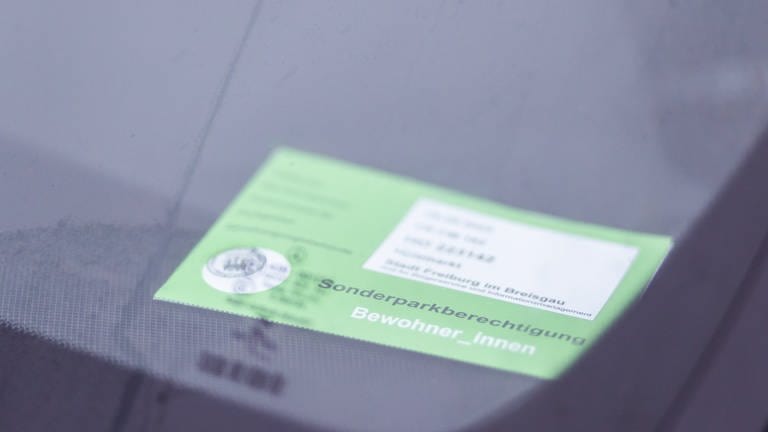 Ein grüner Sonderparkausweis für Anwohnerinnen und Anwohner liegt hinter der Windschutzscheibe eines Autos
