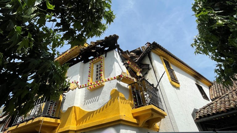 Zu sehen ist der Schaden im Europapark. Ein gelb-weißes Haus aus der spanischen Themenwelt ist von unten fotografiert. Ein Teil des Daches ist eingestürzt.