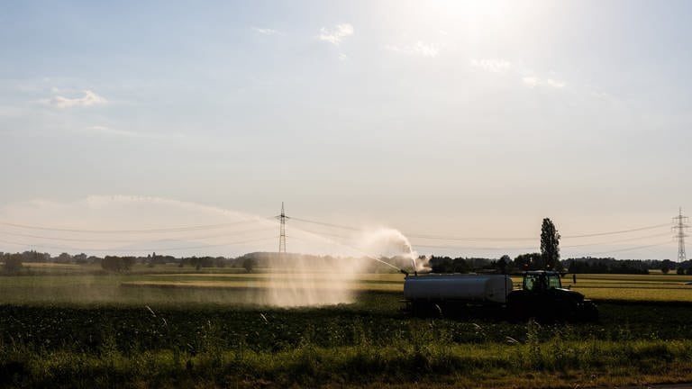 Auf einem Feld steht ein Traktor mit einem Wasseranhänger. Dieser bewässtert das Feld. (Foto: picture-alliance / Reportdienste, Philipp von Ditfurth)