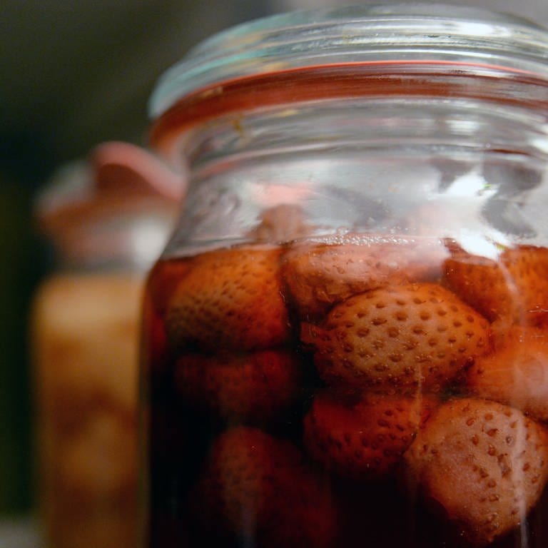 Nahaufnahme von dunkelroten, eingekochten Erdbeeren in einem Weck-Glas.
