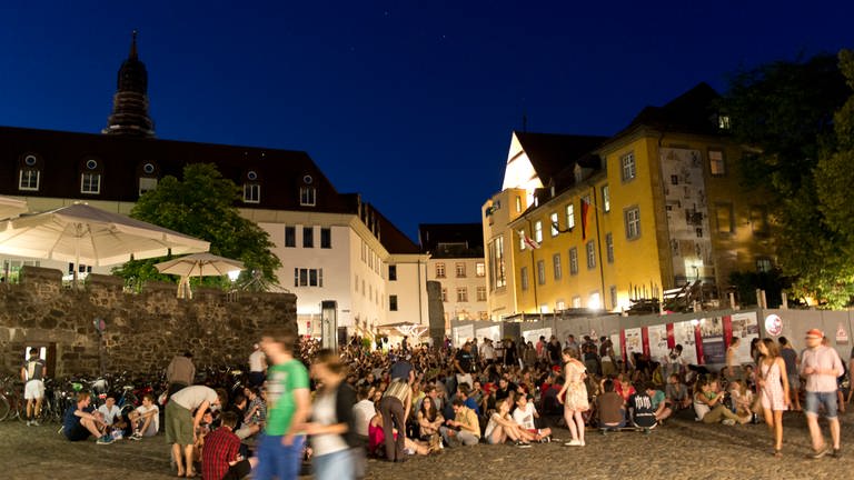 Der Augustinerplatz in Freiburg bei Nacht. Viele Menschen sitzen in Grüppchen auf der Treppe. (Foto: picture-alliance / Reportdienste, picture alliance / dpa | Patrick Seeger)