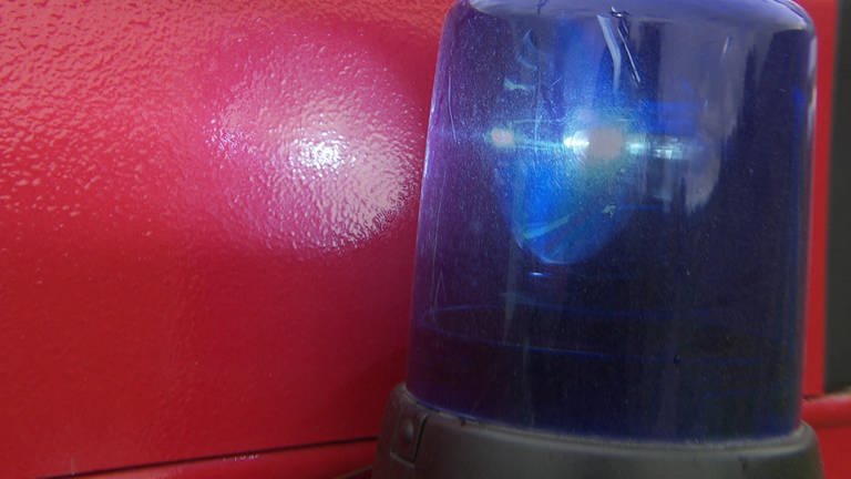 ein Blaulicht vor rotem Hintergrund in Nahaufnahme 