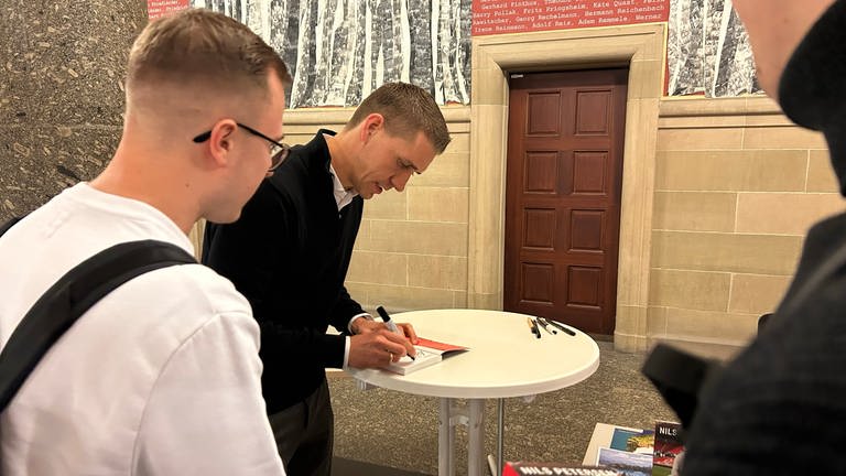 Nils Petersen signiert im Anschluss der Veranstaltung sein Buch für einen Fan