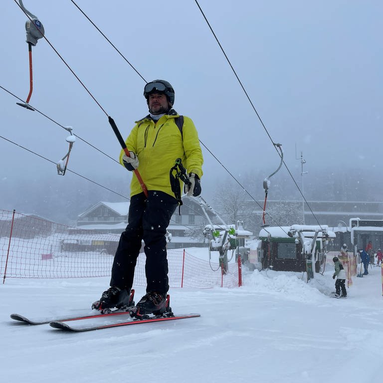 Ein Skifahrer lässt sich in einem Schlepplift eine Feldbergpiste hochziehen. 