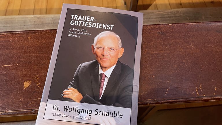 Auf den Plätzen liegen Liedhefte bereit, auf ihnen ist ein Foto von Wolfgang Schäuble abgedruckt. (Foto: SWR)