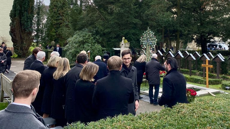 Neben dem Grab steht die Familie von Wolfgang Schäuble, vor ihnen steht ein Mann mit großere Brille und schüttelt die Hände. (Foto: SWR, Ina Held)