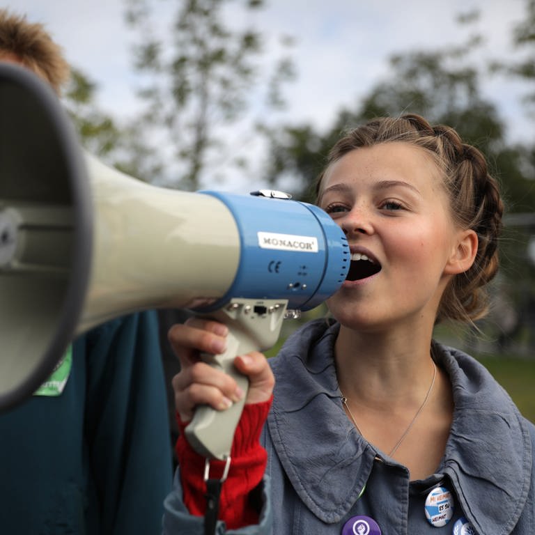 Ein junge Frau spricht in ein Megaphon. (Foto: picture-alliance / Reportdienste, Christoph Soeder)