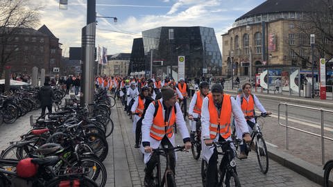 Ärzte der Uniklinik Freiburg sind mit organgenen Warnwesten und weißen Kitteln beim Warnstreik auf ihren Rädern unterwegs (Foto: SWR, Dinah Steinbrink)