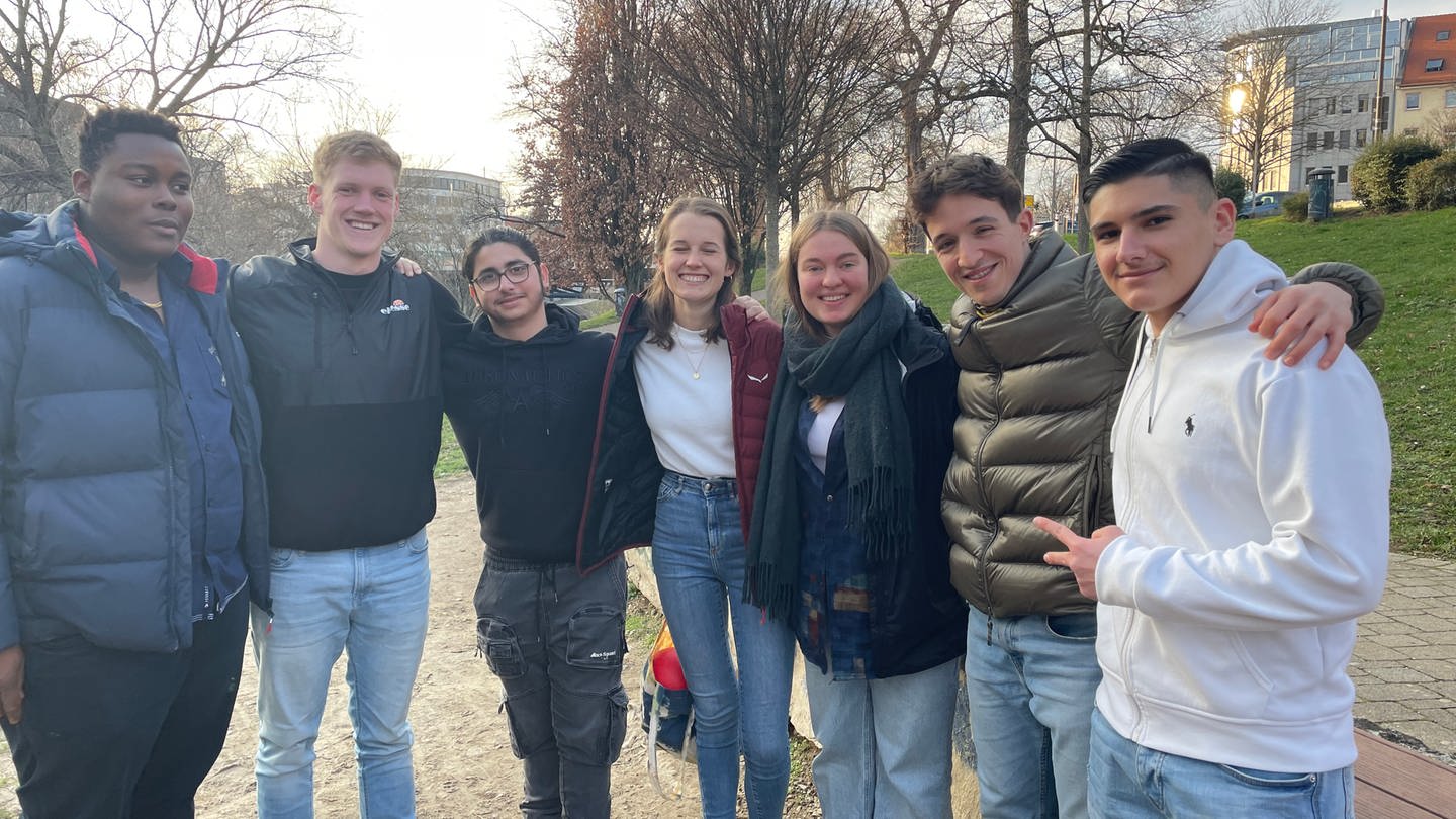 Der 17 Jahre alte Rimon Ali steht in einem Halbkreis aus Freunden und Betreuern des Freiburger Lernprojekts 