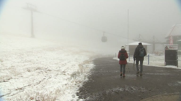 Wanderer laufen auf dem Feldberg durch Niebel und Schneerieseln. (Foto: SWR)