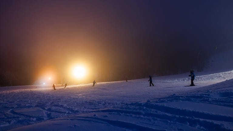 Skifahrer fahren im Schwarzwald nach dem erneuten Wintereinbruch wieder über die Piste.