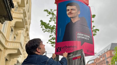 Christian Kröper von "Urbanes Freiburg" hängt ein Plakat seines Mitstreiters Jérémy Schenk auf