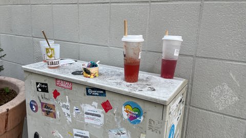 Halbvolle Plastikbecher als Müll auf einem Verteilerkasten abgestellt. (Foto: SWR, Peter Binder)